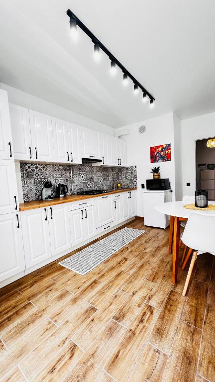 a kitchen with white cabinets and a wooden floor at Luxury apartament Buiucani in Chişinău
