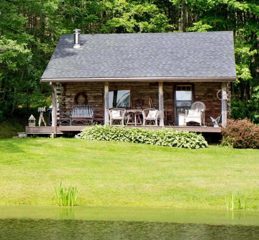 eine Blockhütte mit einem Tisch und Stühlen auf der Veranda in der Unterkunft Cozy Cottage on Pond in Great Valley