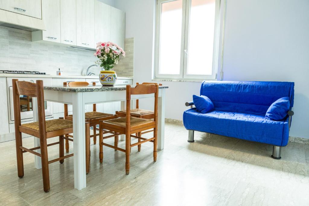 uma cozinha com um sofá azul e uma mesa e cadeiras em Rifugio dell'Amore e Pace em Magliano Vetere