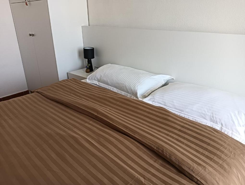 een slaapkamer met een groot bed en een bruine deken bij Seaside Deluxe Apartment in Durrës