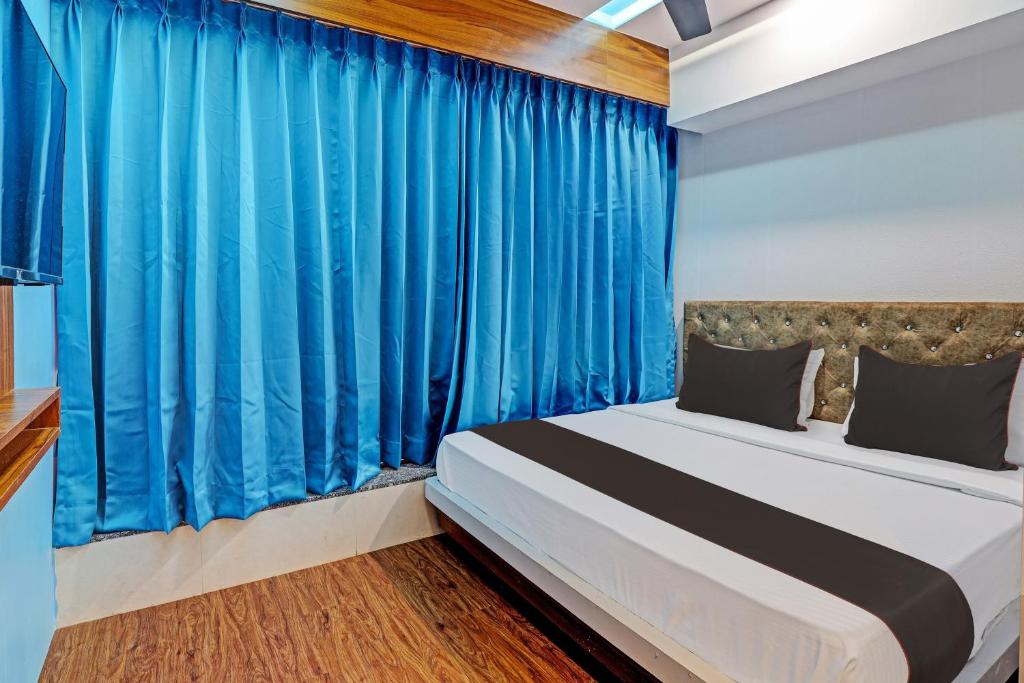 a bedroom with a bed with blue curtains at Hotel Glaace Inn Near Delhi Airport in New Delhi