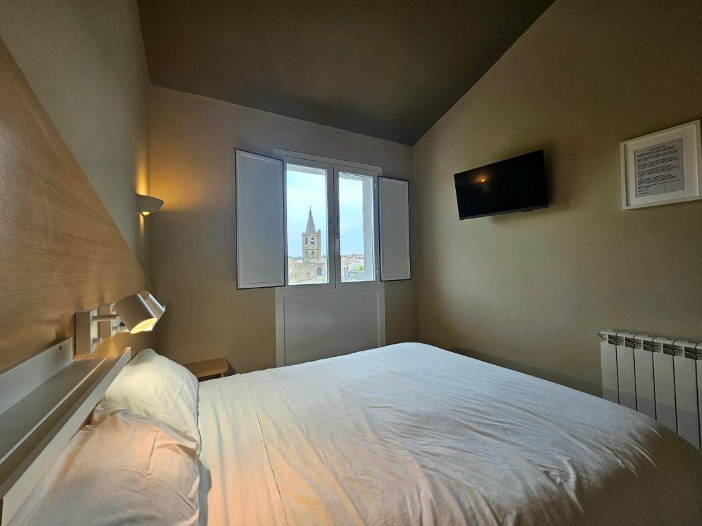Un dormitorio con una gran cama blanca y una ventana en Hostal JP y Apartamentos, en Sangüesa