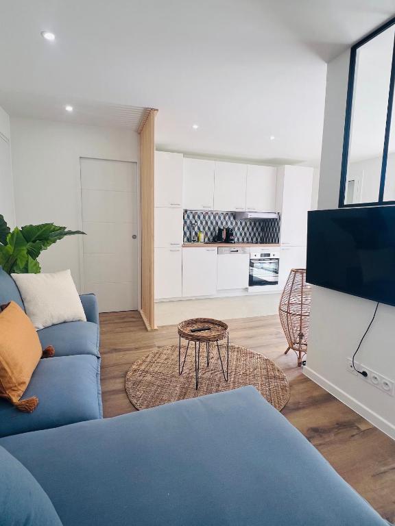 un salon avec un canapé bleu et une télévision dans l'établissement Les Appartements De Lina - Appartement Patz - Self Check-In -, à La Grande Motte