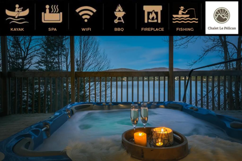a jacuzzi tub with two candles and two wine glasses at Chalet Le Pélican in Lac-Superieur