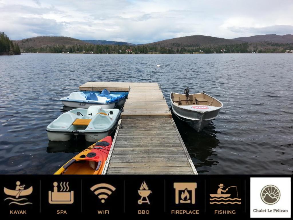 three boats are docked at a dock on a lake at Chalet Le Pélican in Lac-Superieur