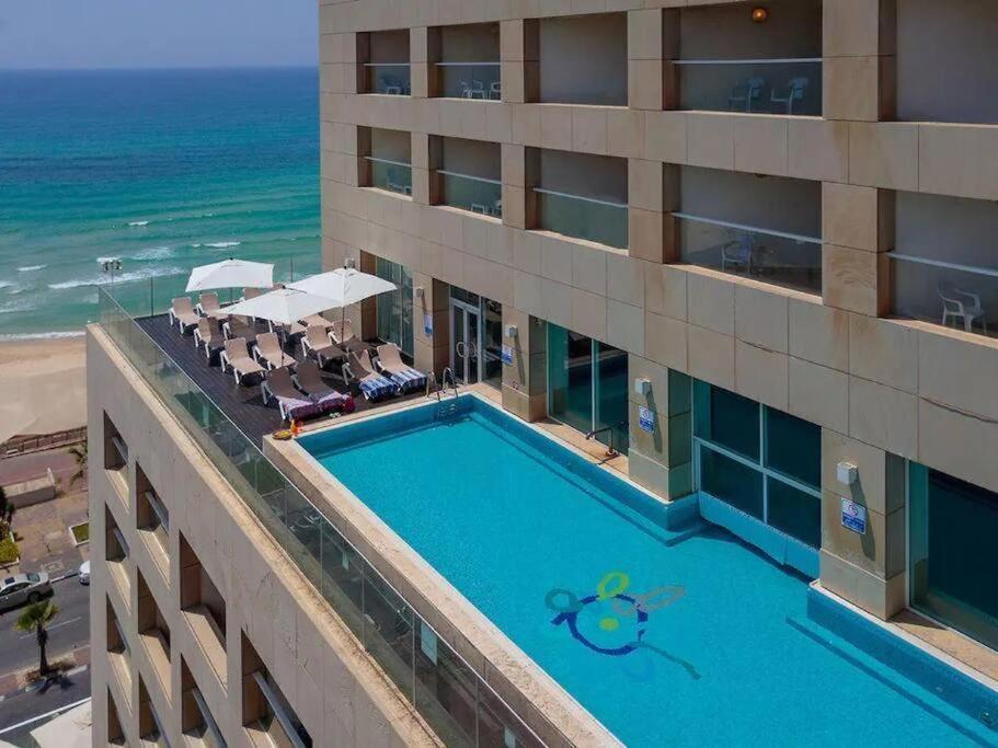 an overhead view of a hotel with a swimming pool and the ocean at Leonardo hotel , Very luxury suite, high floor, in fron of See in Bat Yam