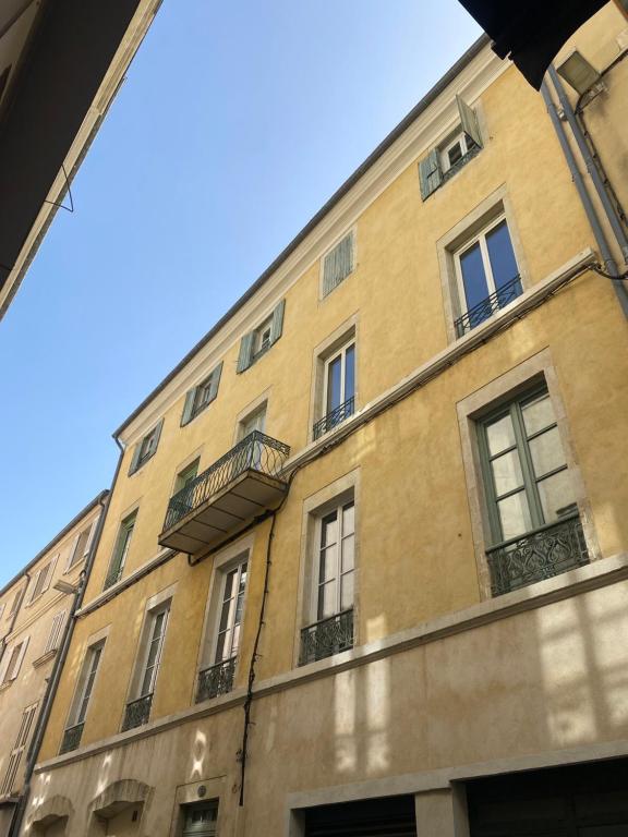 Edificio alto con ventanas y balcón en La Halte des Arènes de Nîmes Emeraude, Havre de paix en ville en Nimes