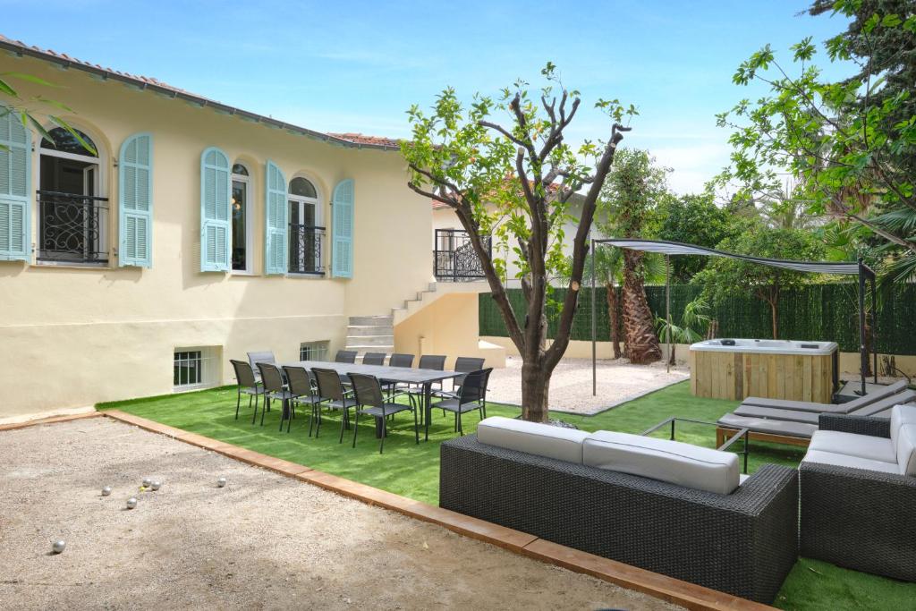 a patio with a table and chairs in a yard at VILLA DES PERGOLAS -6 Bdrs - 5 bathrs -Parking -Jardin -JACUZZI -TRAMstation , 10 min beach in Nice