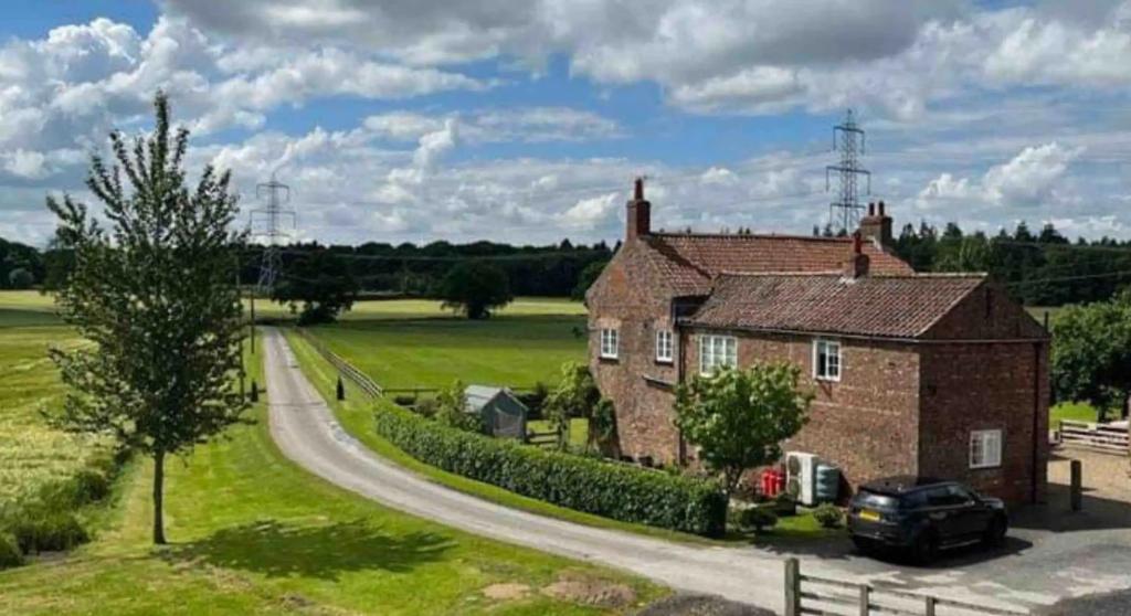 une maison en briques avec une voiture garée à côté d'une route dans l'établissement Beech cottage ~ close to York ~ cozy rural stay, à Stamford Bridge