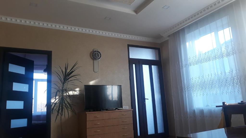 ein Wohnzimmer mit einem TV auf einer Kommode mit Fenstern in der Unterkunft House Mary in Stepanawan