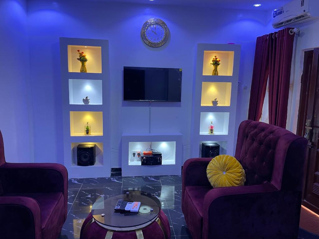 a living room with two chairs and a tv on a wall at belphus Apartment in Lagos