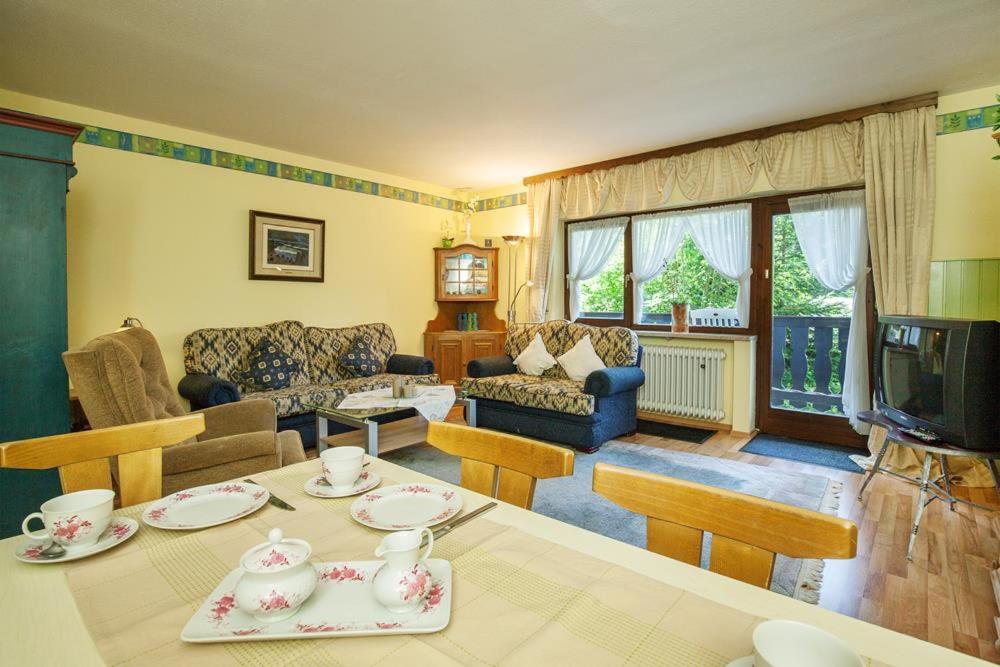 ein Wohnzimmer mit einem Tisch, einem Sofa und einem TV in der Unterkunft Ferienwohnung Alex in Reit im Winkl