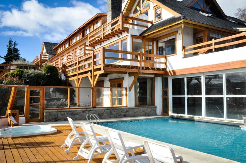 una casa con piscina frente a una casa en Apart del Lago en San Carlos de Bariloche