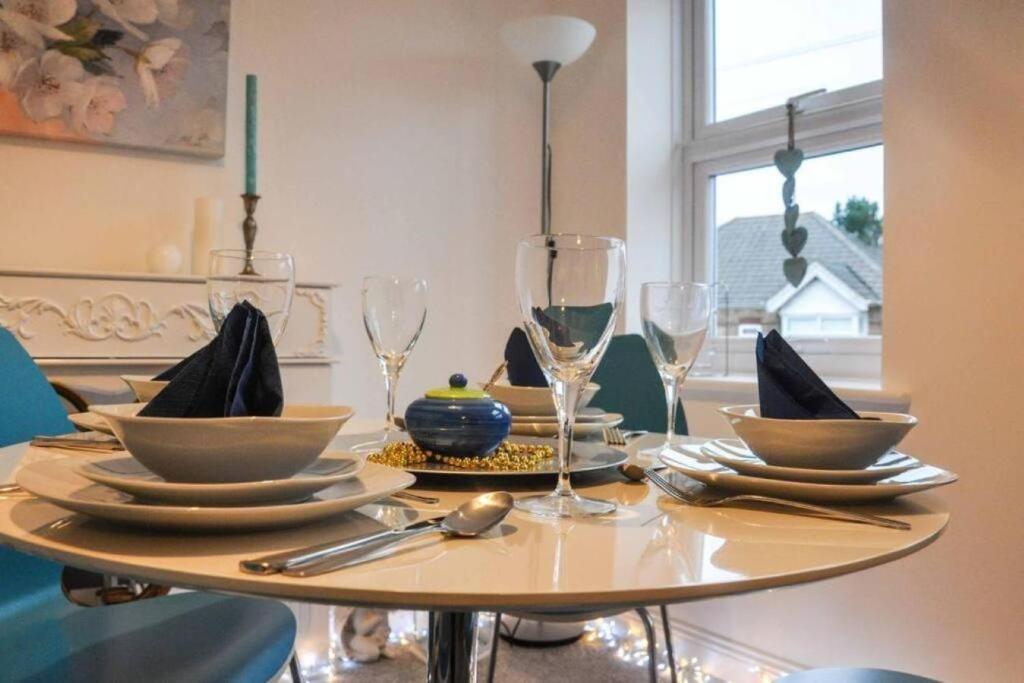 a table with plates and wine glasses on it at The Sashes - Apartment Two - FREE Parking - Ultrafast WIFI - Smart TV - Netflix - sleeps up to 6! Close to Poole Town Center & Sandbanks & Bournemouth in Poole