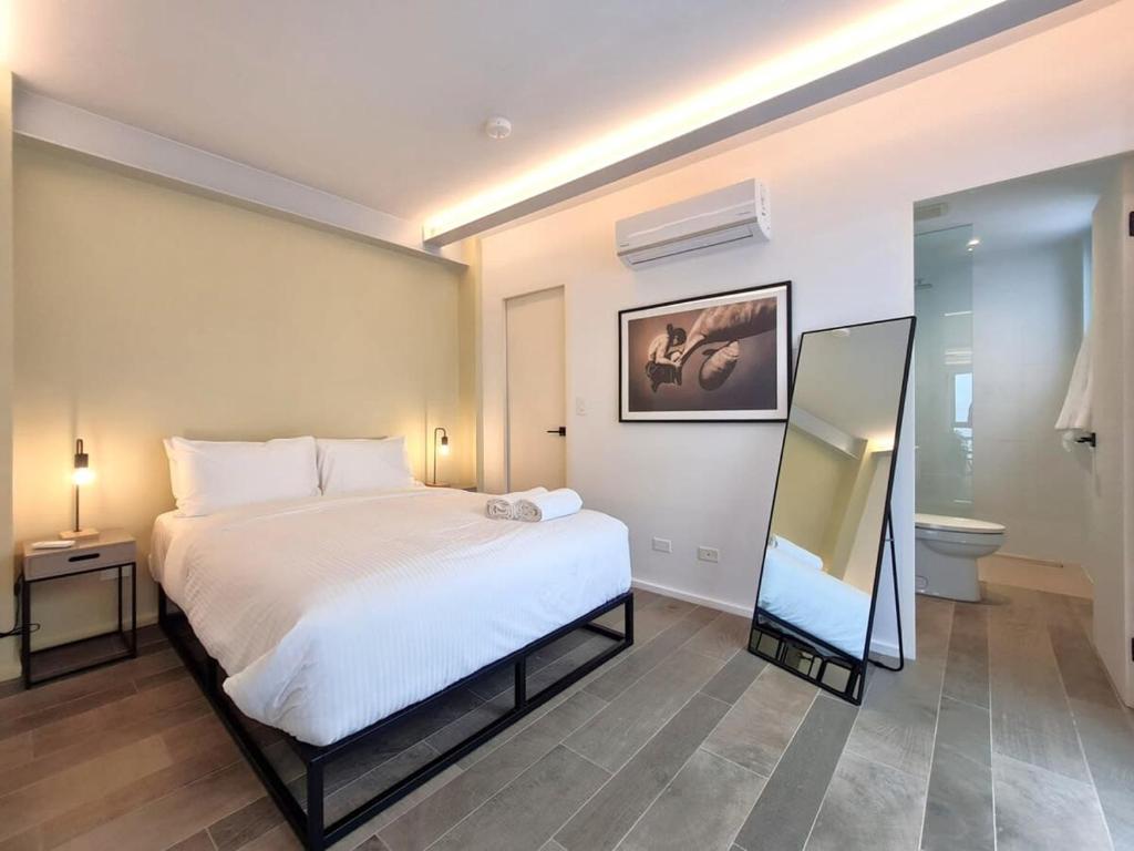 a bedroom with a large white bed and a mirror at Charming 2BR With Pool in Casco Antiguo in Panama City