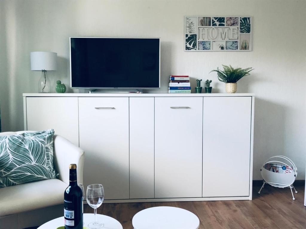 una sala de estar con un armario blanco con TV. en Eifel-House - FeWo, en Weilerswist