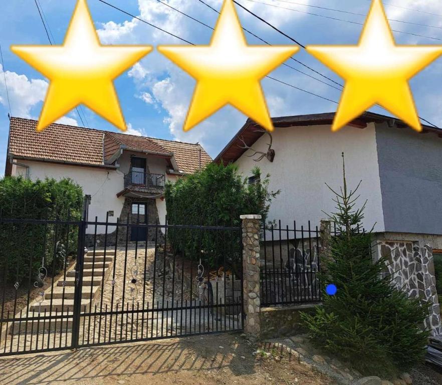 four yellow stars hanging over a fence in front of a house at Villa Luiza in Şura Mare