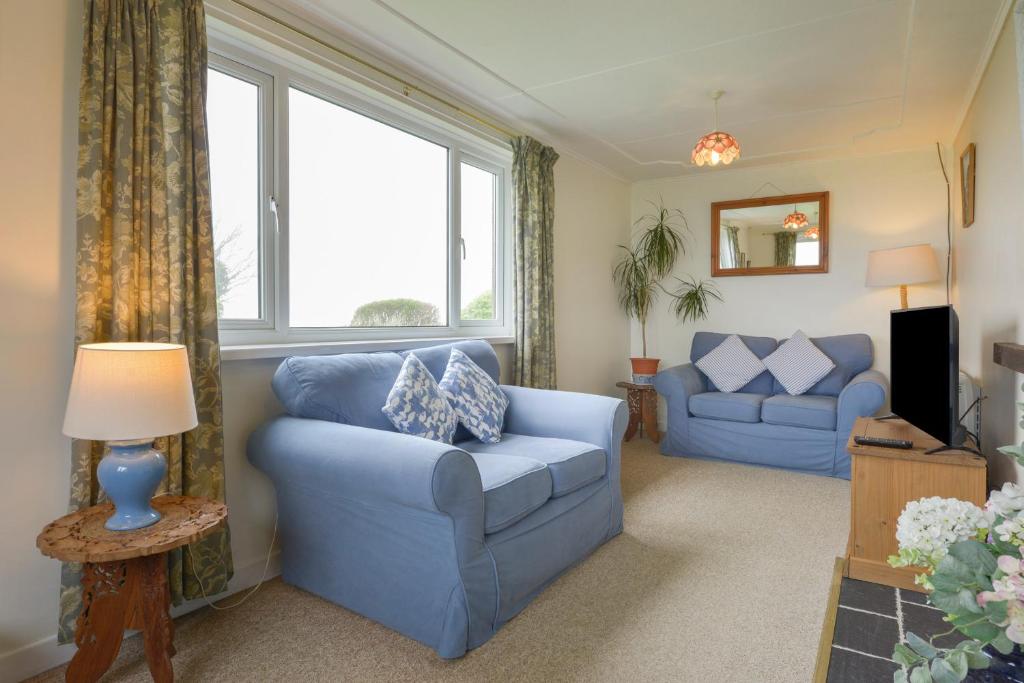 a living room with two blue couches and a window at The Quillet in Penzance