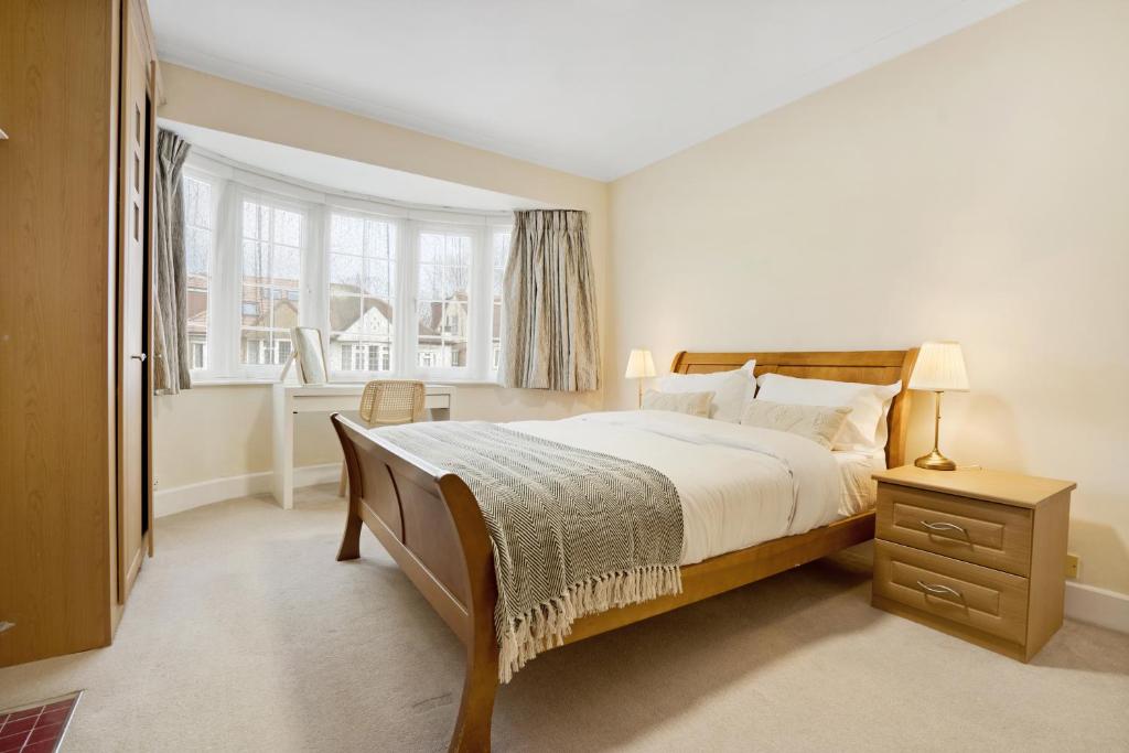 um quarto com uma cama grande e uma janela em 5 bed with parking and large private garden em Finchley