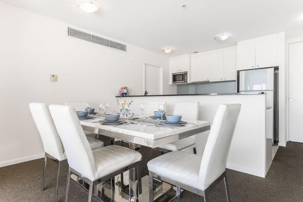 a white kitchen with a dining table and white chairs at A Spacious 2BR Apt with an Amazing View Over Darling Harbour in Sydney