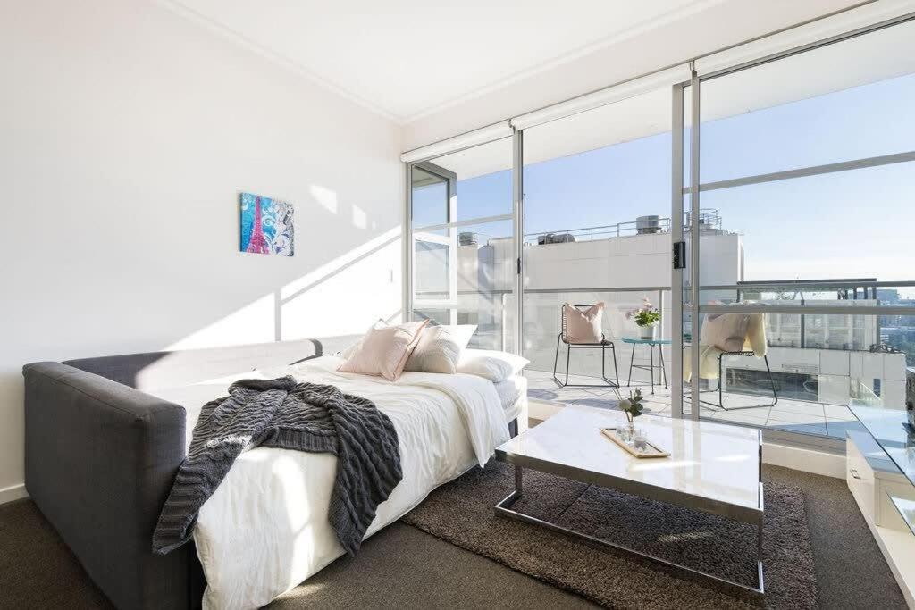 a white bedroom with a bed and a table at A Spacious 2BR Apt with an Amazing View Over Darling Harbour in Sydney