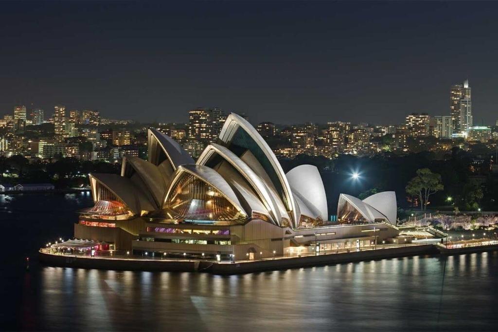 a view of the sydney opera house at night at A Spacious 2BR Apt with an Amazing View Over Darling Harbour in Sydney