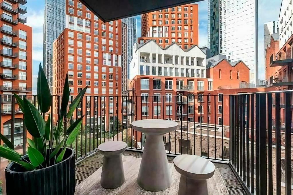a balcony with a table and stools and a view of a city at Executive Luxury apartment in Vauxhall with balcony in London