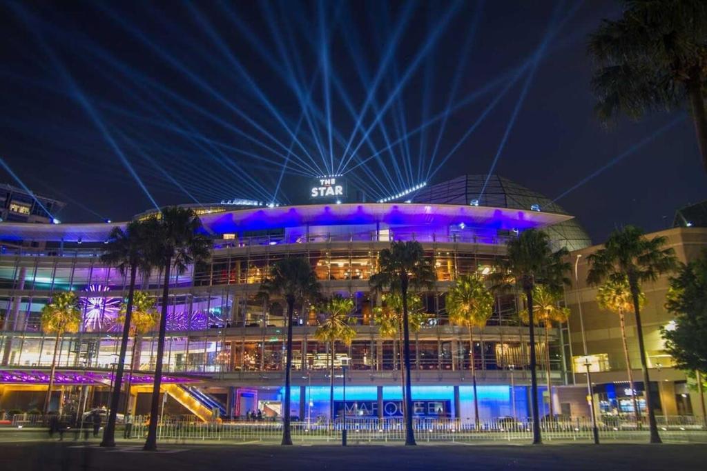 a large building with blue lights on it at night at A Spacious 2BR Apt with an Amazing View Over Darling Harbour in Sydney