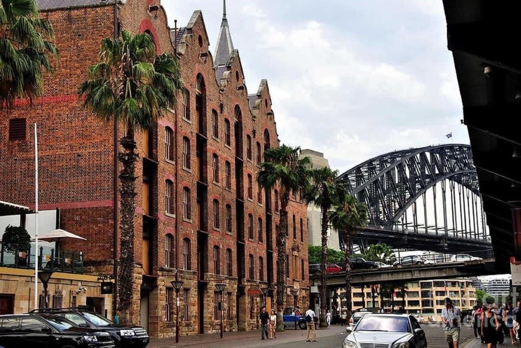 a large red brick building with a bridge in the background at A Spacious 2BR Apt with an Amazing View Over Darling Harbour in Sydney