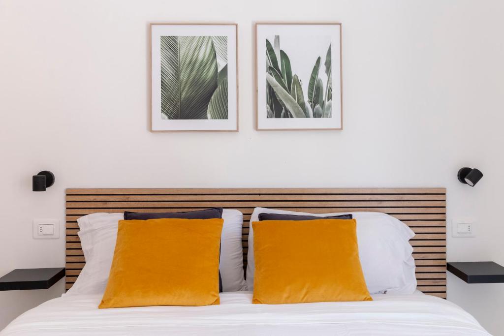 uma cama com duas almofadas laranja e duas fotografias na parede em Shiny Rooms Verona em Verona