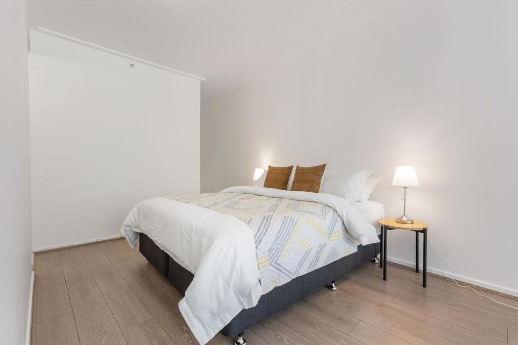 um quarto branco com uma cama e uma mesa lateral em A Cozy & Modern Studio Right Next to Darling Harbour em Sydney