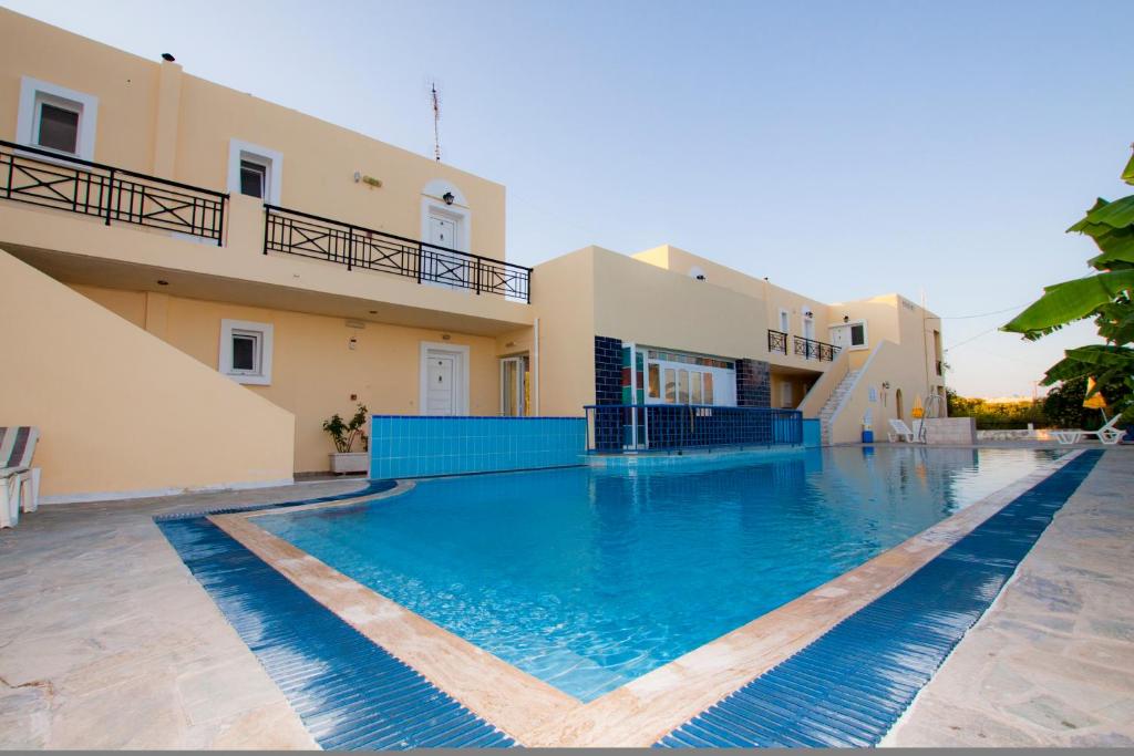 a large swimming pool in front of a house at Manine Apartments in Kos