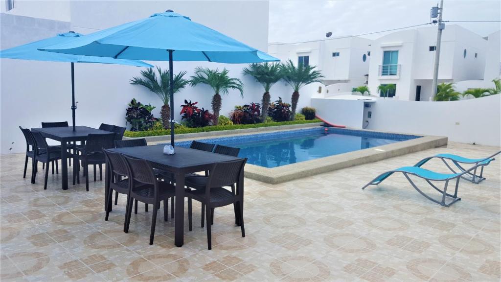 - deux tables et chaises avec parasols à côté de la piscine dans l'établissement Casa con piscina en urbanización privada, à Salinas