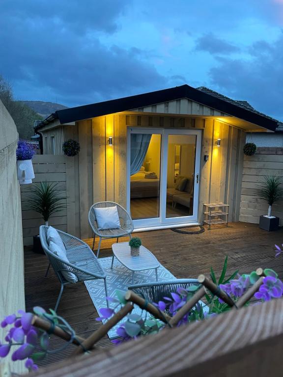 a house with a deck with chairs and a patio at The Grove Cabin in Fort William