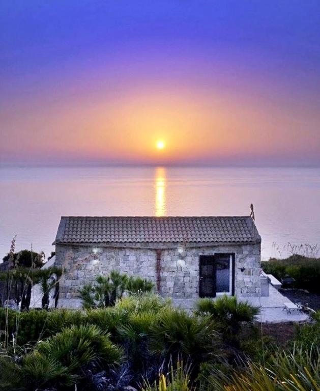 a stone building with the sunset in the background at Chalet Tango in Contrada Sauci Grande