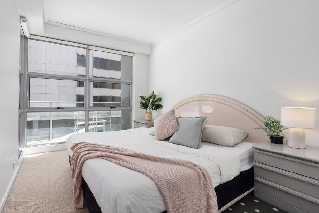 una camera da letto con un letto grande e una finestra di A Comfy 2BR Apt for 7 Next to Darling Harbour a Sydney