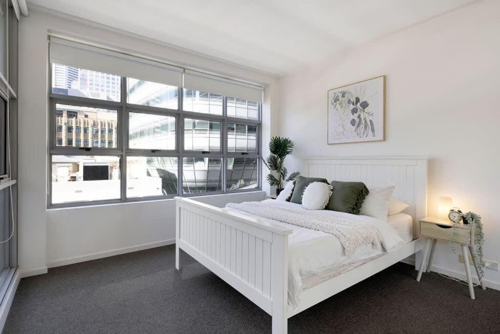 a white bedroom with a white bed and a window at A Stylish & Bright Suite Next to Darling Harbour in Sydney