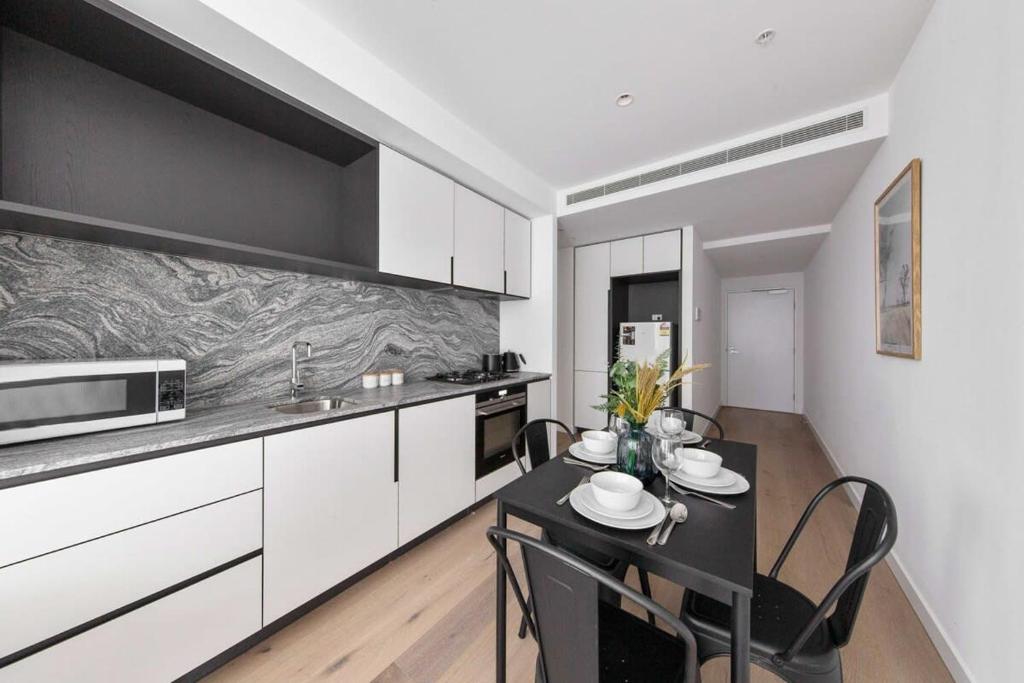 une cuisine avec des armoires blanches et une table avec des chaises dans l'établissement A Lux & Modern Apt Next to Southern Cross Station, à Melbourne