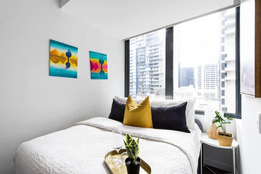 ein Schlafzimmer mit einem Bett und einem großen Fenster in der Unterkunft A Stylish CBD Studio Right Next to Southern Cross in Melbourne
