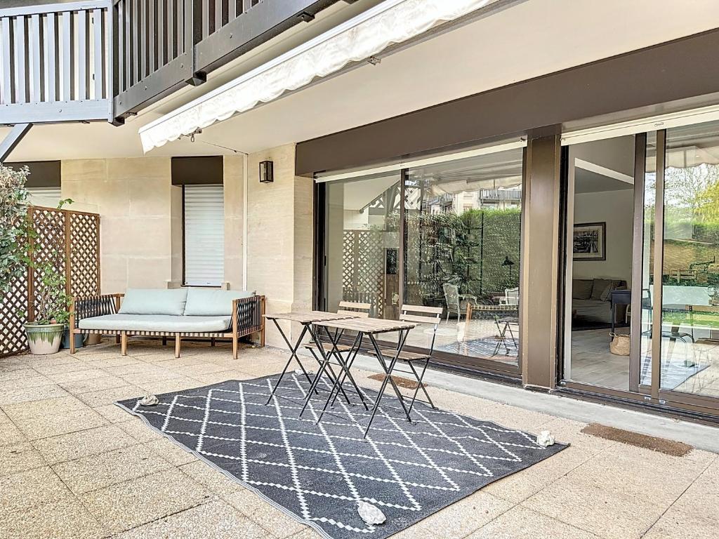 d'une terrasse avec une table et un banc. dans l'établissement Garden's YourHostHelper, à Deauville