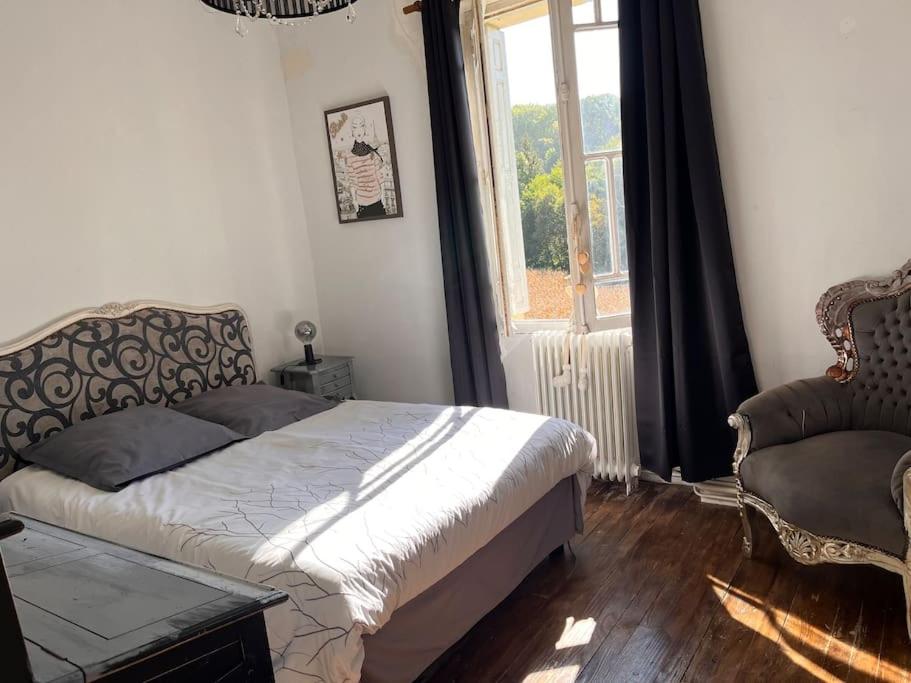 een slaapkamer met een bed, een stoel en een raam bij La périgourdine et son spa in Saint-Cyprien