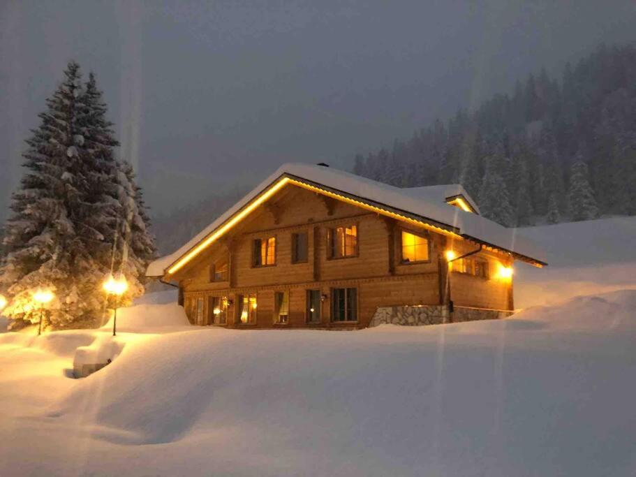 a log cabin in the snow with a christmas tree at Chalet Riedhuus in Davos Wolfgang