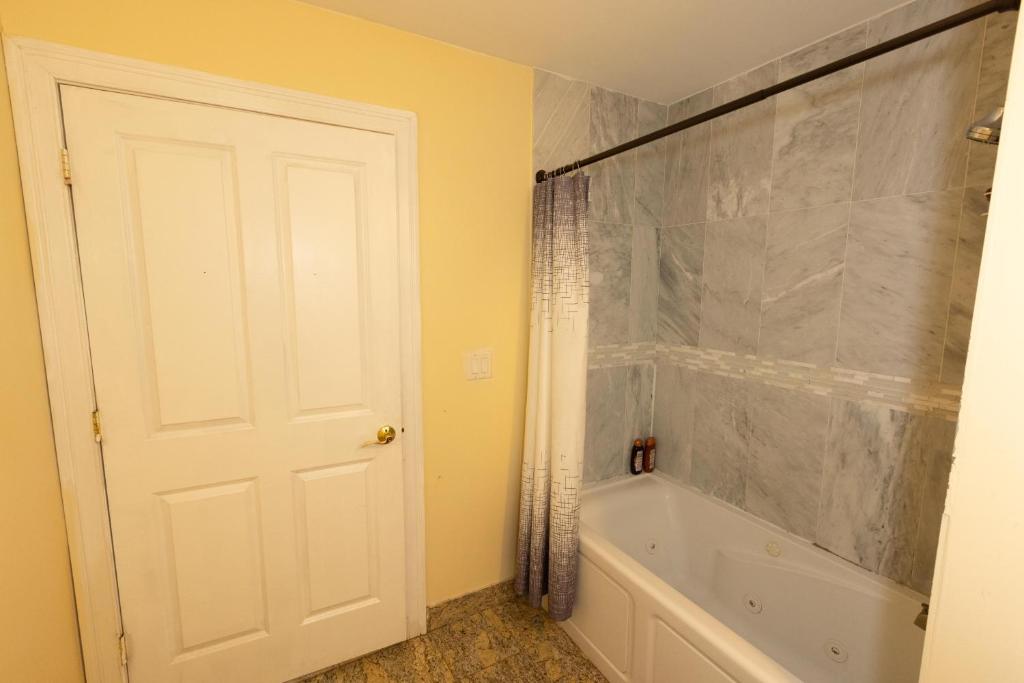 聯城的住宿－Luxurious 3-Bed Apt - mins to NYC，浴室配有白色门和浴缸。