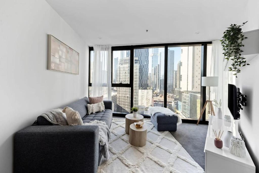 a living room with a couch and a large window at A Stylish & Cozy Apt Near Crown with City Views in Melbourne