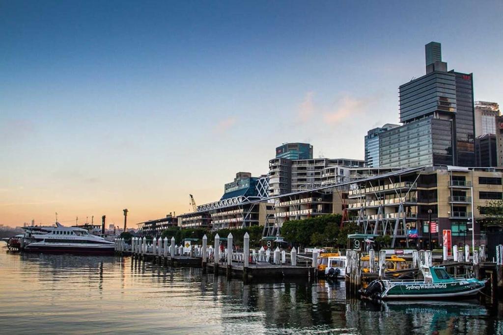 a group of boats docked at a dock in a city at A Comfy 2BR Apt Right Next to Darling Harbour in Sydney
