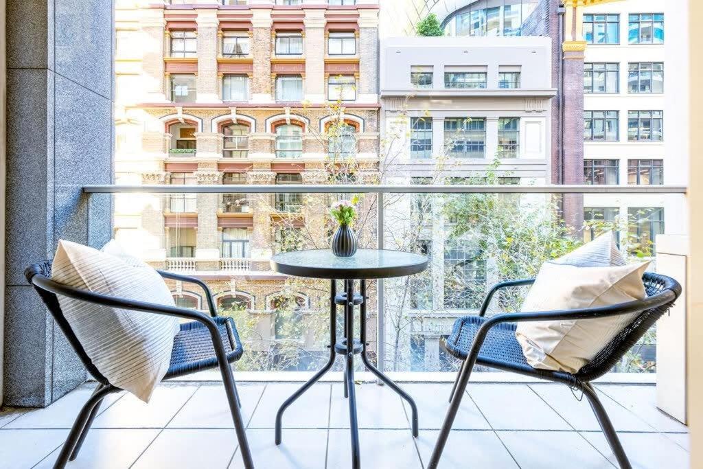 uma mesa e 2 cadeiras numa varanda com uma janela em A Comfy Studio for 6 Next to Darling Harbour em Sidney