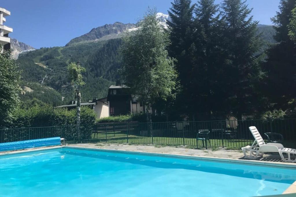 a blue swimming pool with mountains in the background at Starton furnished flat in Chamonix