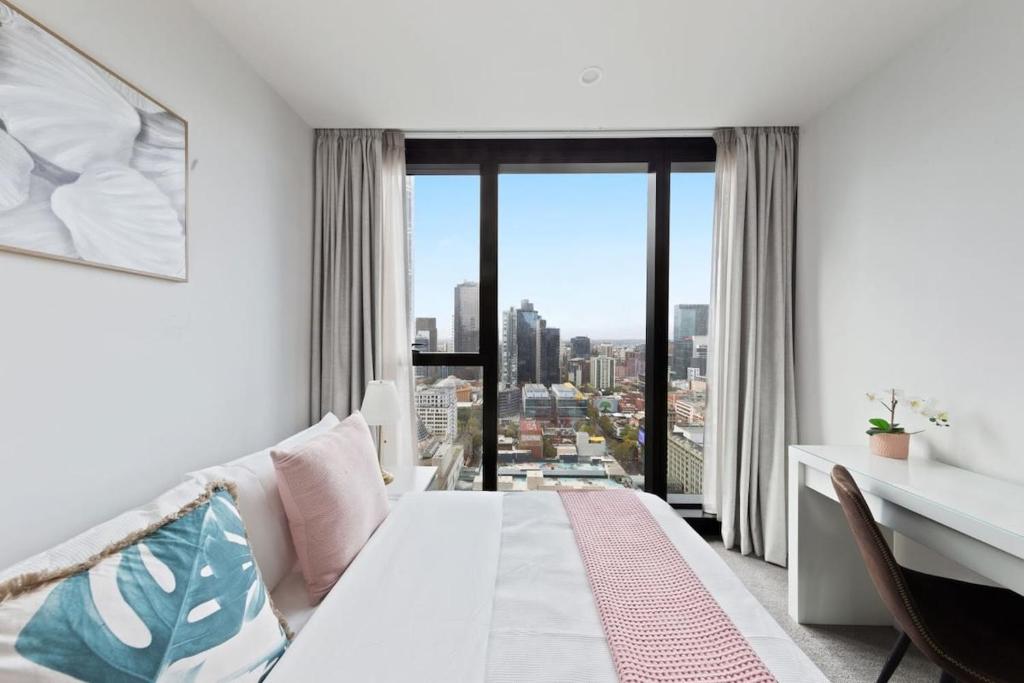 a bedroom with a bed and a desk and a window at A Chic 2BR Apt Near Melbourne CBD w FREE Parking in Melbourne