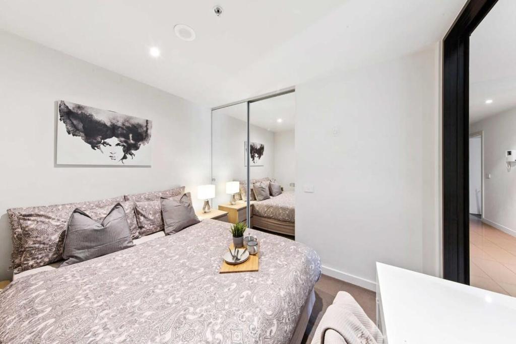a white bedroom with a bed and a couch at Rb4 801-20 Coro in Melbourne