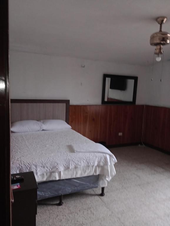 1 dormitorio con 1 cama y TV de pantalla plana en Mundo Hostal, en Guatemala